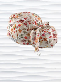 Ponytail style surgical scrub cap with an assortment of autumn eaves in fall colors all over a light background, finished with a ribbon tie, and displayed on a white mannequin head.