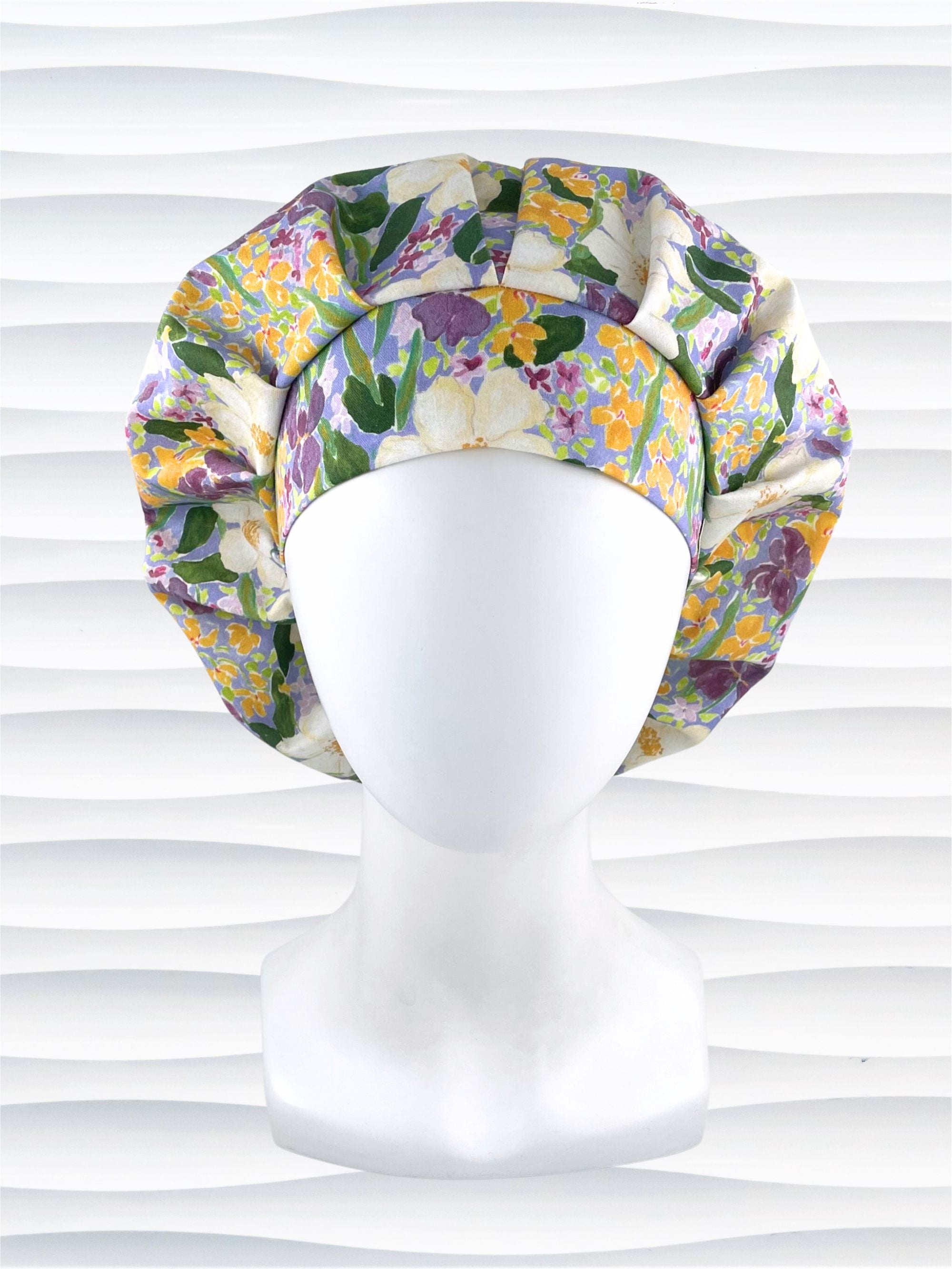 Bouffant style surgical scrub cap hat with Mardi Gras colors of yellows, greens, and purples on white cotton fabric.