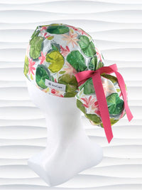 Ponytail style surgical Scrub Cap hat for long or medium hair with lilies floating on a lily pond in pinks and greens on a white cotton fabric.