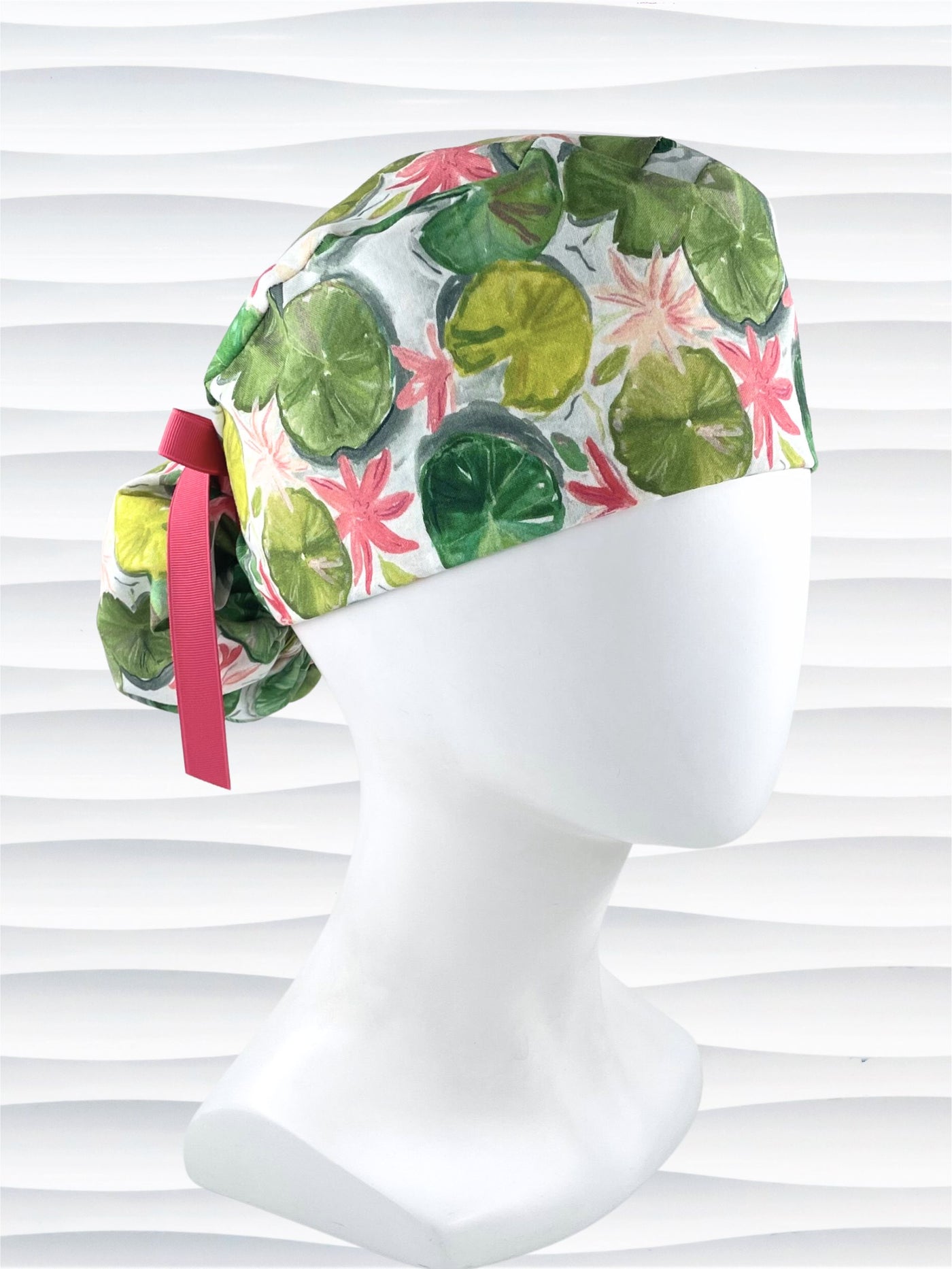 Ponytail style surgical Scrub Cap hat for long or medium hair with lilies floating on a lily pond in pinks and greens on a white cotton fabric.
