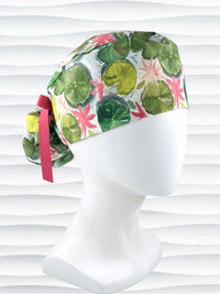 Ponytail style surgical Scrub Cap hat for long or medium hair with lilies floating on a lily pond in pinks and greens on a white cotton fabric.