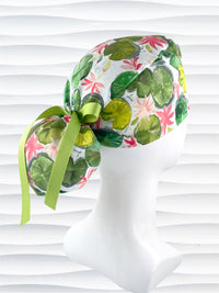Ponytail style surgical Scrub Cap hat for long or medium hair with lilies floating on a lily pond in pinks and greens on a white cotton fabric.