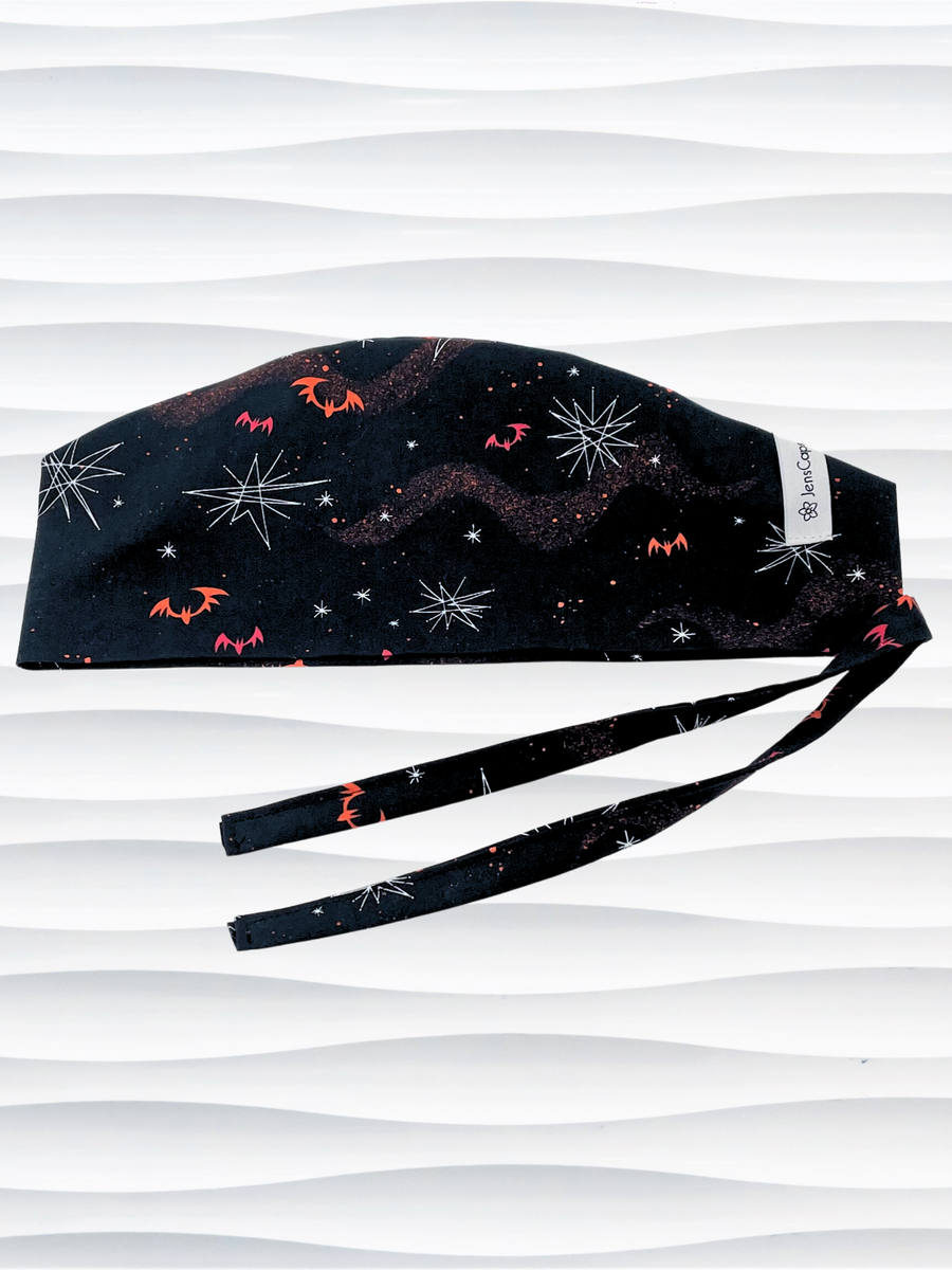 Surgeon style men's surgical scrub cap hat with red and orange bats and white stars on black cotton fabric.