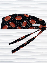 Surgeon style surgical scrub cap hat with footballs and Xs and Os tossed all over this black cotton premium fabric.