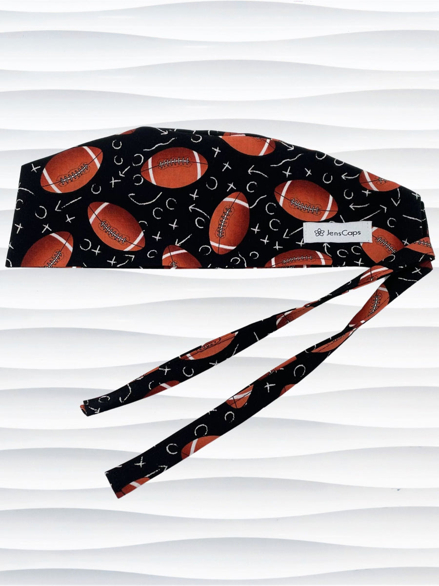 Surgeon style surgical scrub cap hat with footballs and Xs and Os tossed all over this black cotton premium fabric.