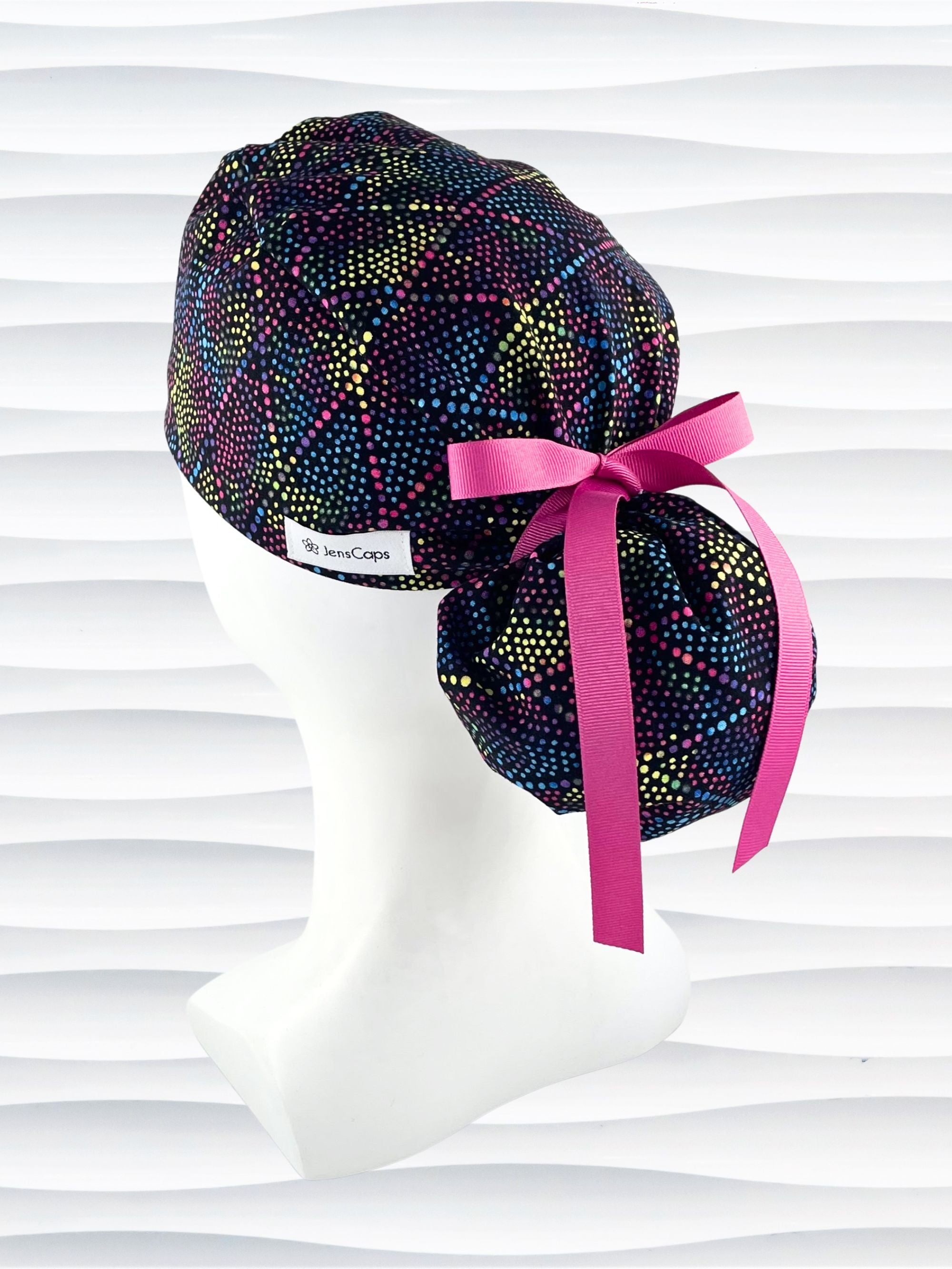 Ponytail style surgical scrub cap hat with bright colored dots and lines in diamond shapes on black cotton fabric.