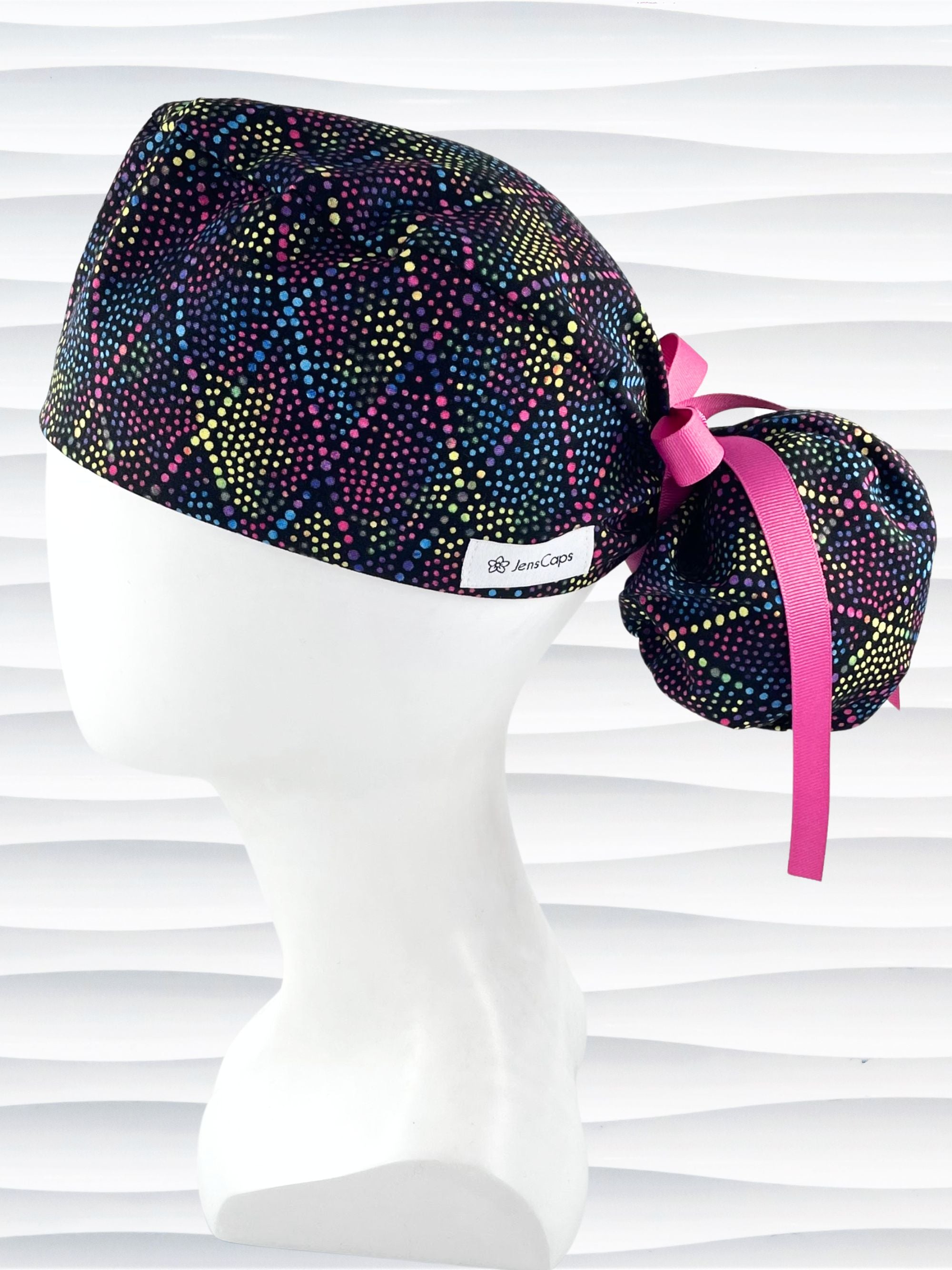 Ponytail style surgical scrub cap hat with bright colored dots and lines in diamond shapes on black cotton fabric.