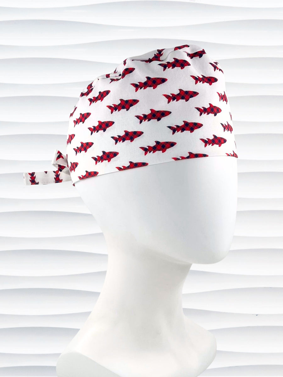 Surgeon style surgical scrub cap hat with red buffalo plaid sharks on white cotton fabric.