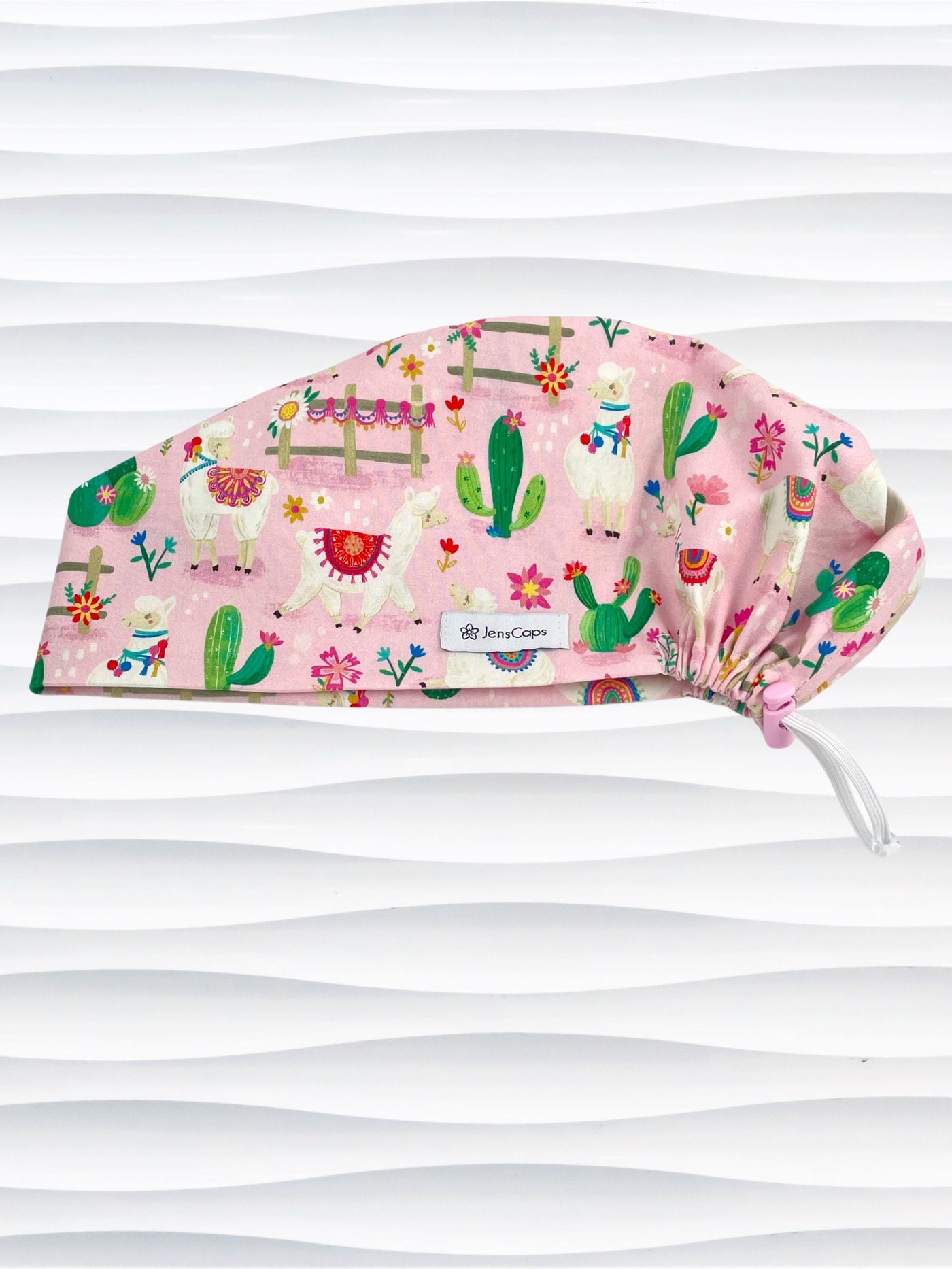Pixie Euro style surgical scrub cap hat with white llamas wearing blankets, pink and blue flowers, and green cactus on pink cotton fabric.