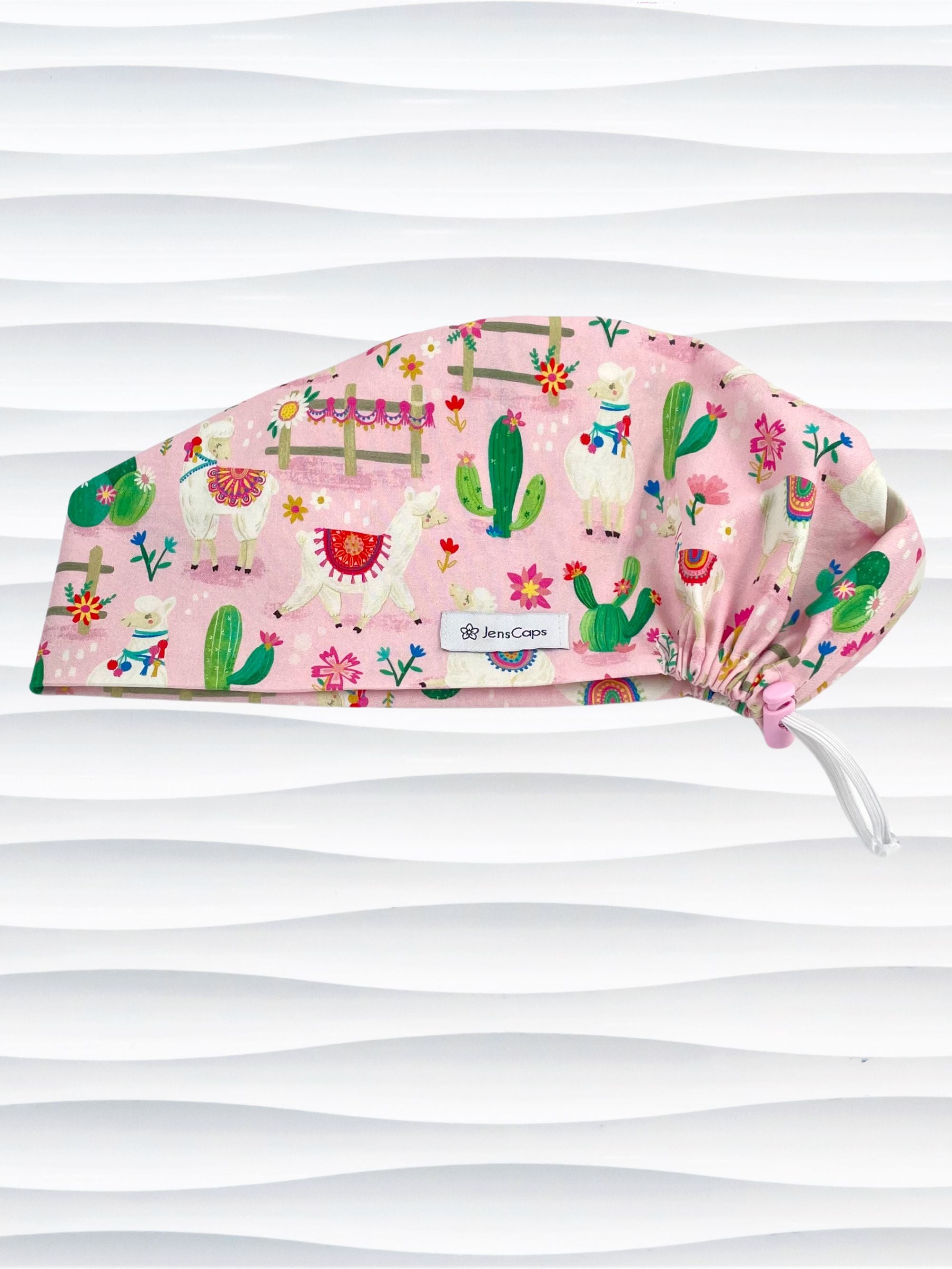Pixie Euro style surgical scrub cap hat with white llamas wearing blankets, pink and blue flowers, and green cactus on pink cotton fabric.