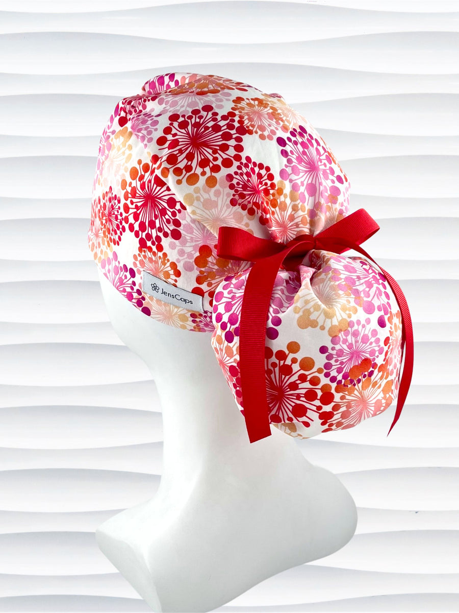 Ponytail style scrub cap with pink and red and orange allium flowers on white cotton fabric and finished with choice of grosgrain ribbon color