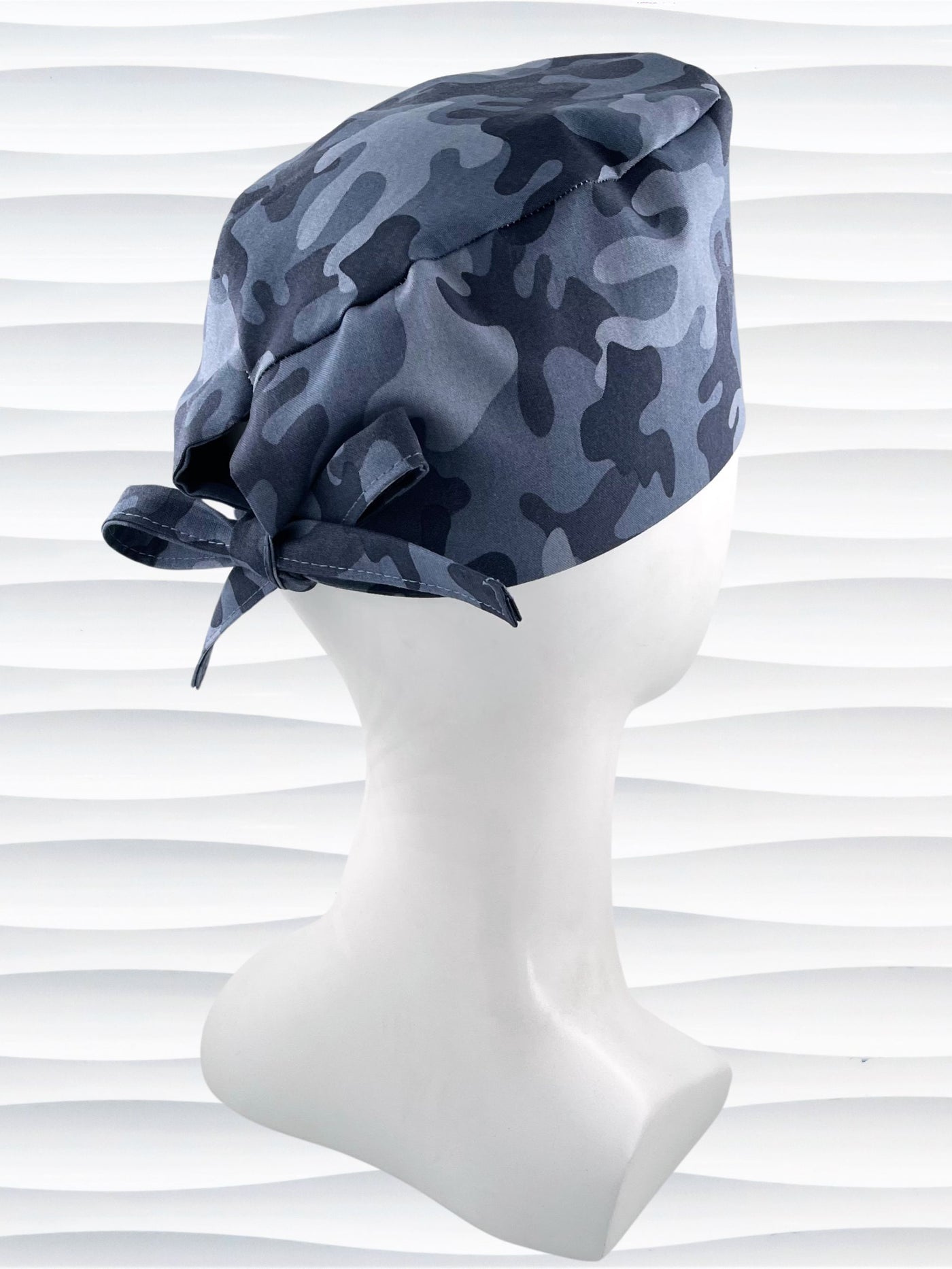 Surgeon style surgical scrub cap hat with an allover print of a steely blue gray camouflage on cotton fabric.