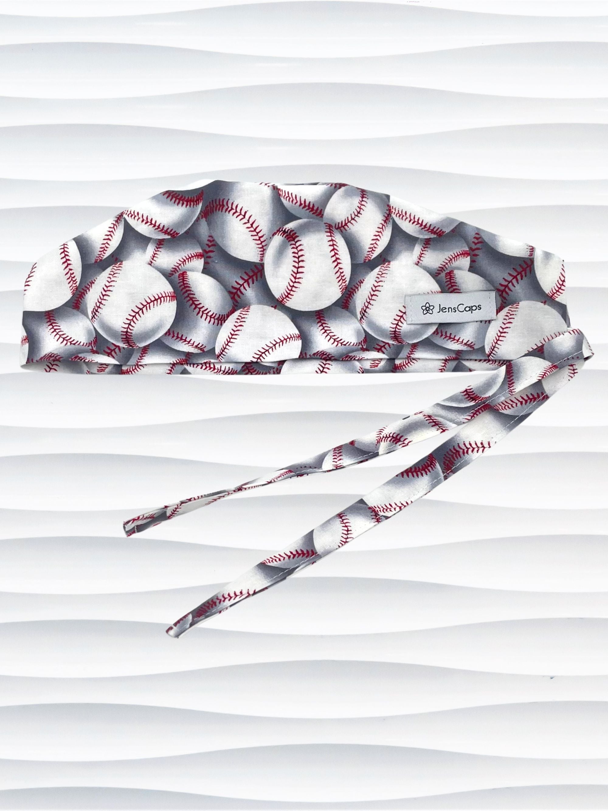 Surgeon style surgical scrub cap hat with an allover print of white baseballs with red stitching and gray shadows on cotton fabric.