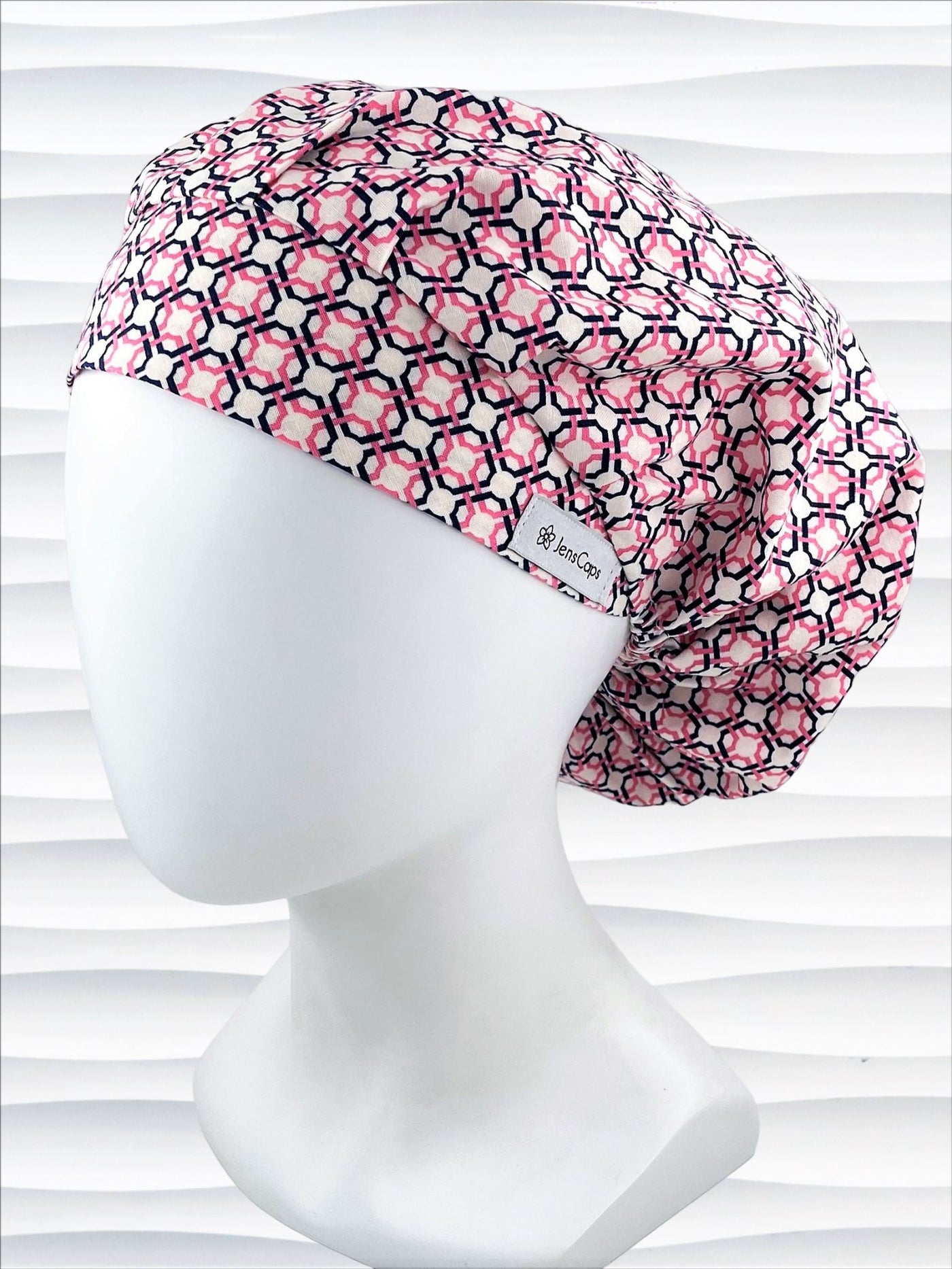 Bouffant style surgical scrub cap hat with pink and blue circles and squares in a trellis pattern on cotton fabric.